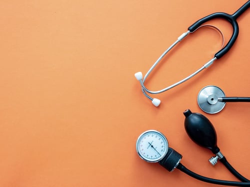 Stethoscope and sphygmomanometer placed on top of an orange table