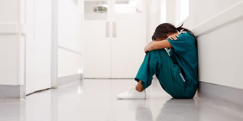 Burned out nurse sitting on the floor crying