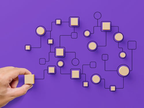 Hand placing wooden pieces on a purple background to symbolize workflows