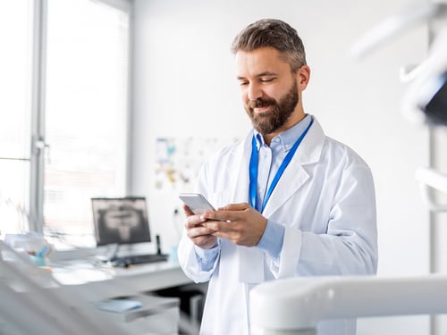 Adult male doctor using his smart phone to prescribe medications