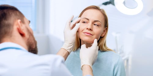 Adult woman having her face examined by doctor