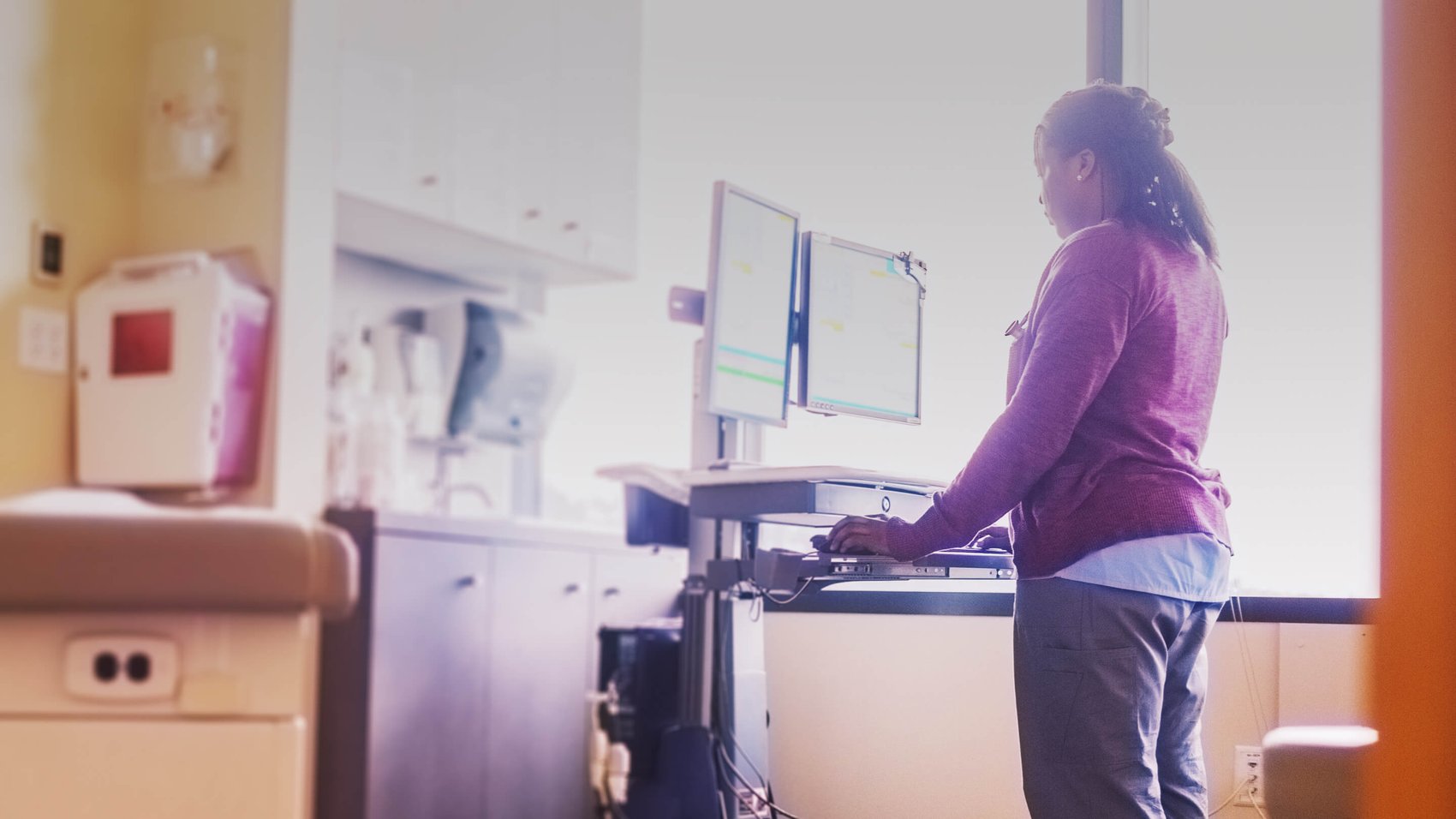 Clinician working on a computer on wheels in a hospital room