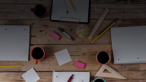 Work table with office supplies and coffee mugs