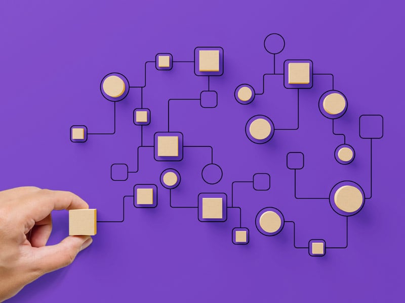 Hand placing wooden pieces on a purple background to symbolize workflows